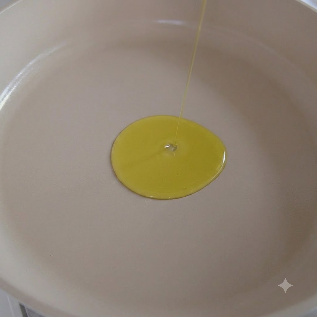 Olive oil being poured into a white pan with garlic sautéing inside.
