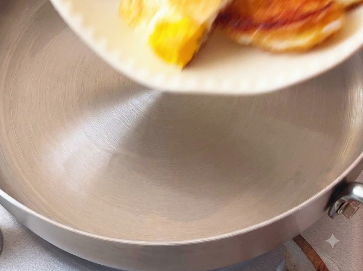 Pieces of fried egg being dropped into a cooking pot from a white dish.