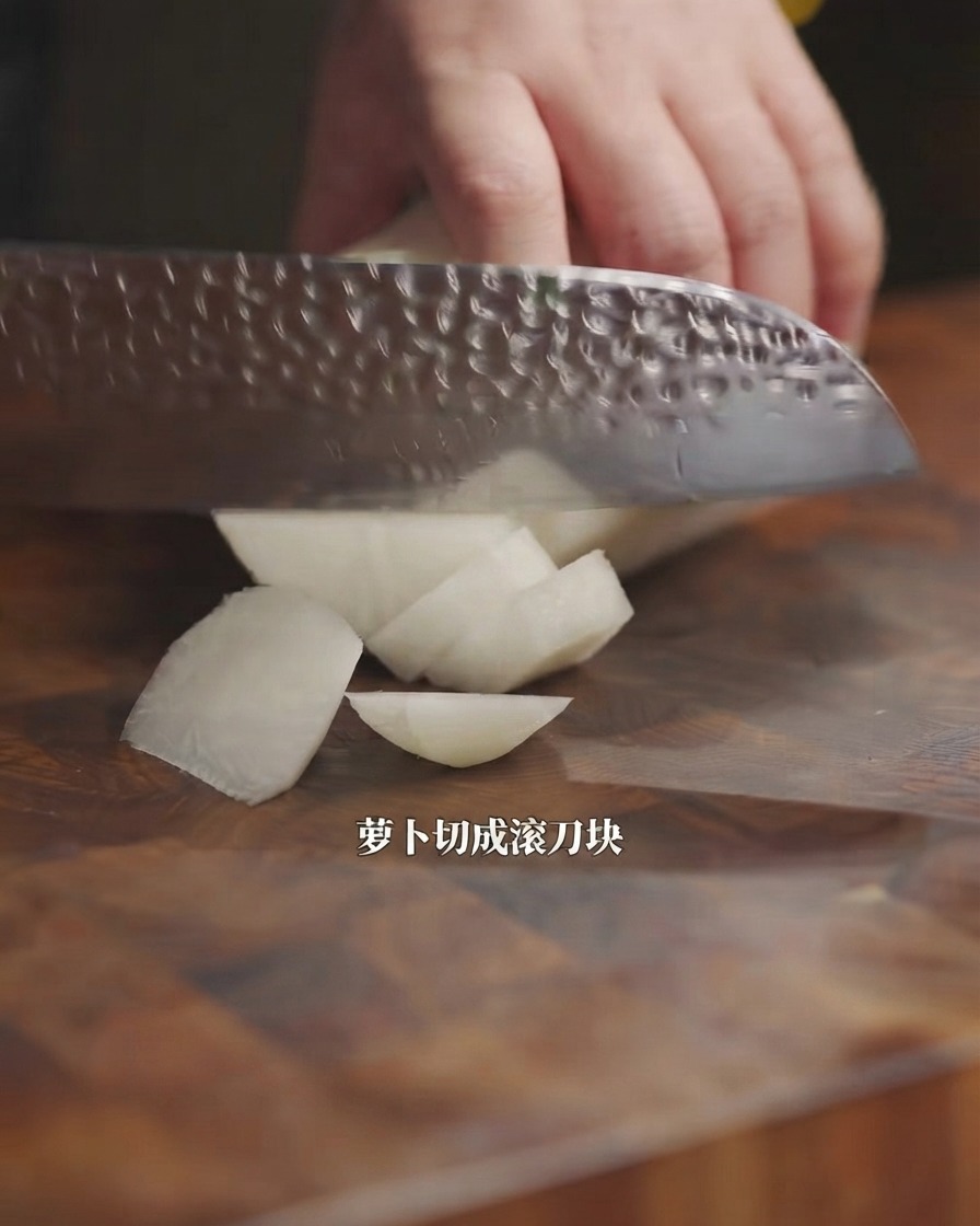 A kitchen knife cutting a white radish into chunks on a wooden board.