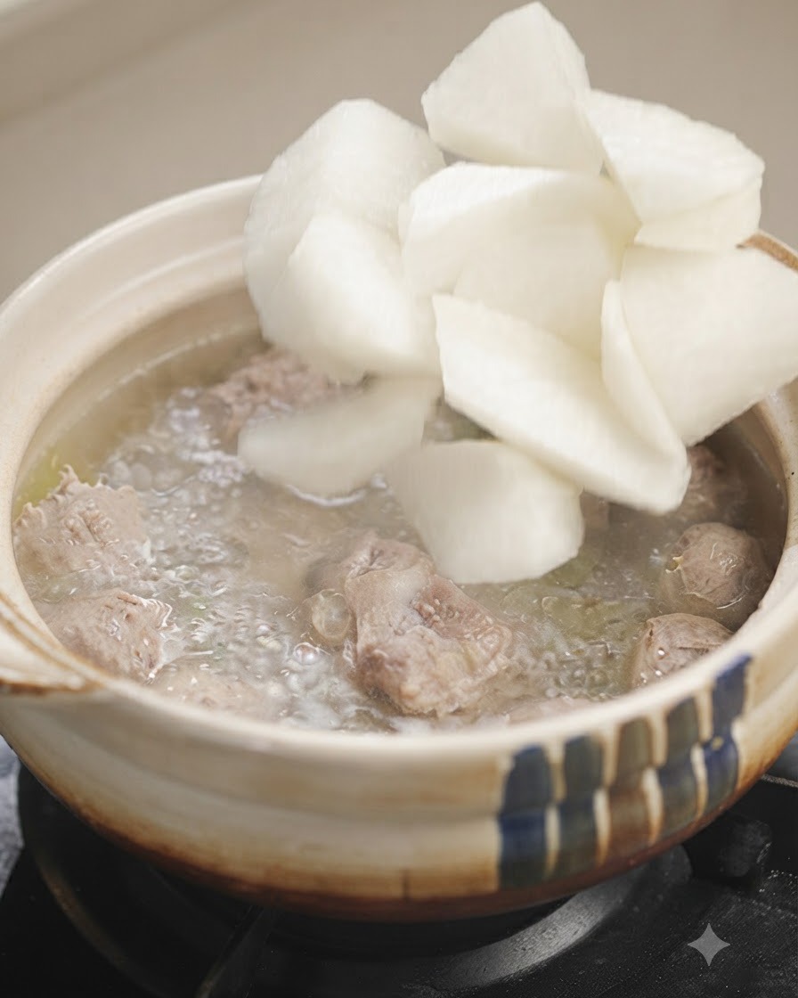 White radish chunks being added into a pot of bubbling soup.