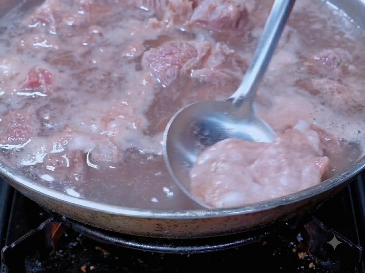 A ladle skimming blood foam from boiling beef in a cooking pot.