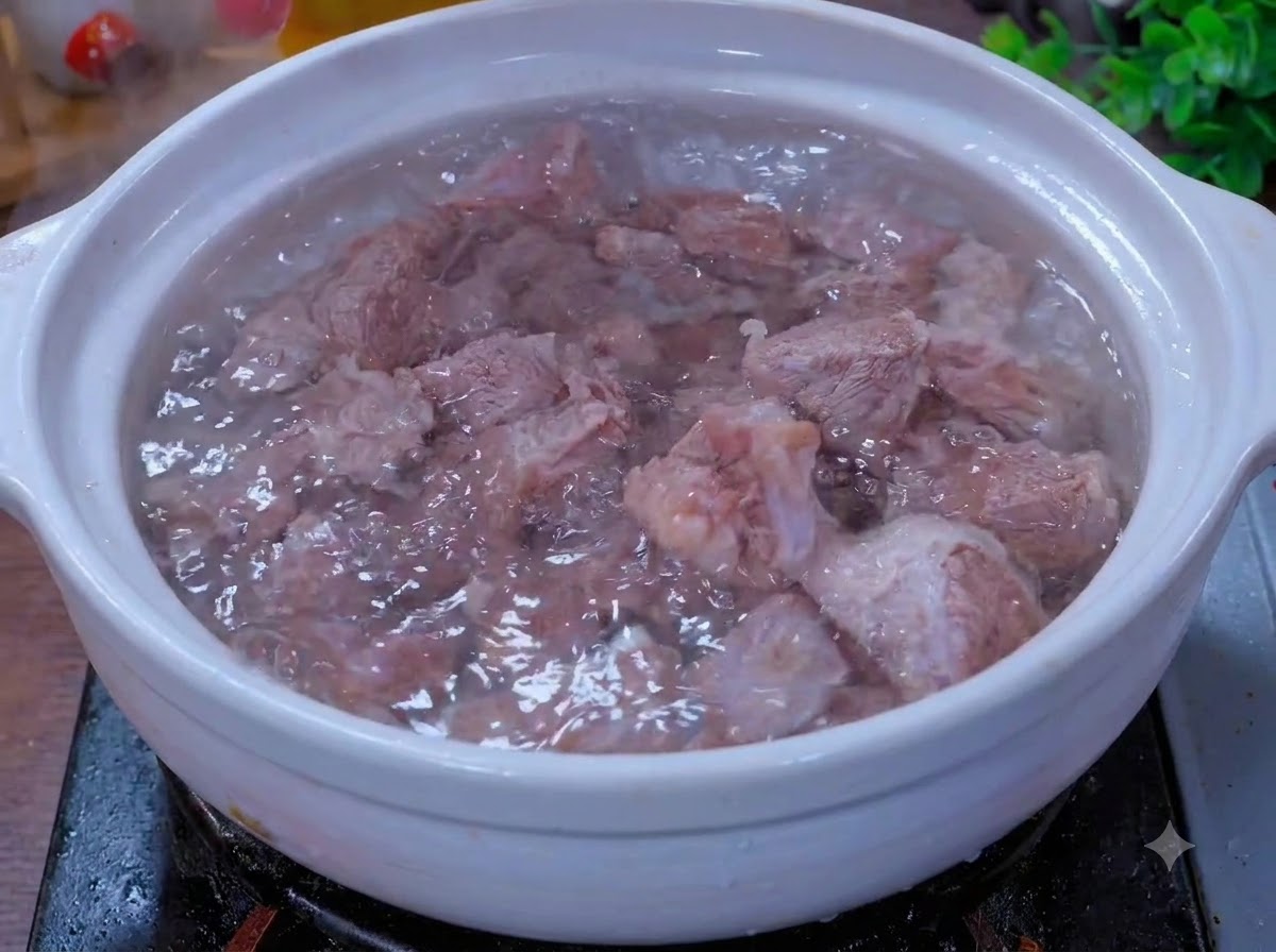 Beef pieces simmering in a white clay pot with aromatics.