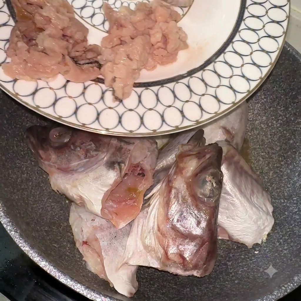 Pollack fish pieces and heads being transferred from a patterned plate into a pan.