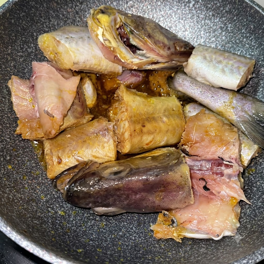 Pollack pieces searing in the pan alongside sliced yellow potatoes.