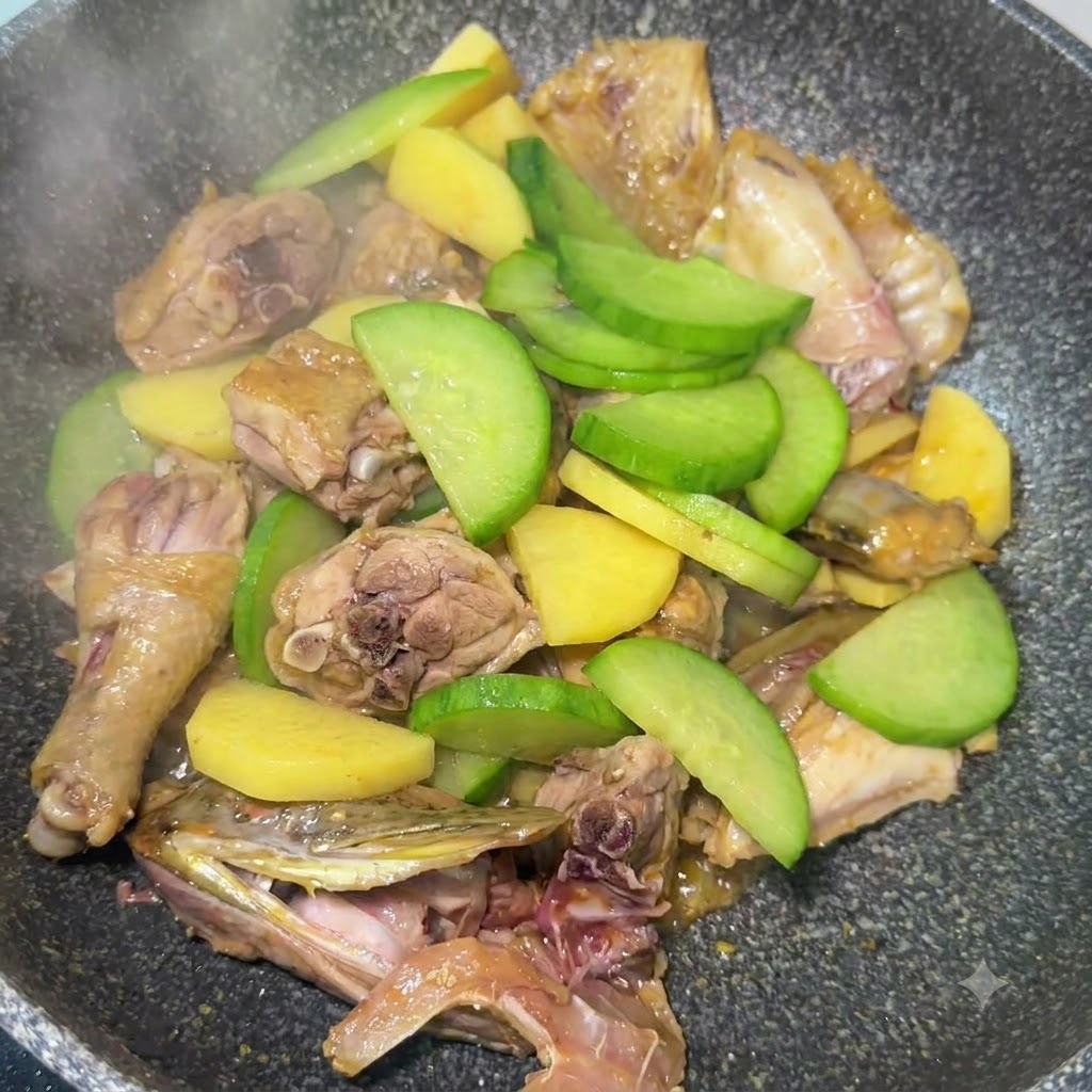 Sliced green radish mixed with potatoes and fish pieces being stir-fried in the pan.