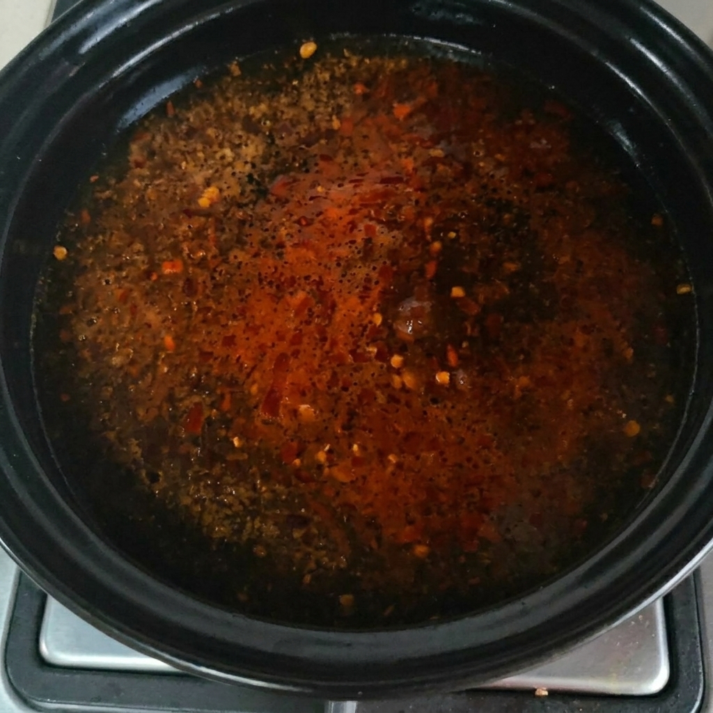 Beef powder seasoning being sprinkled over the bubbling soup surface.