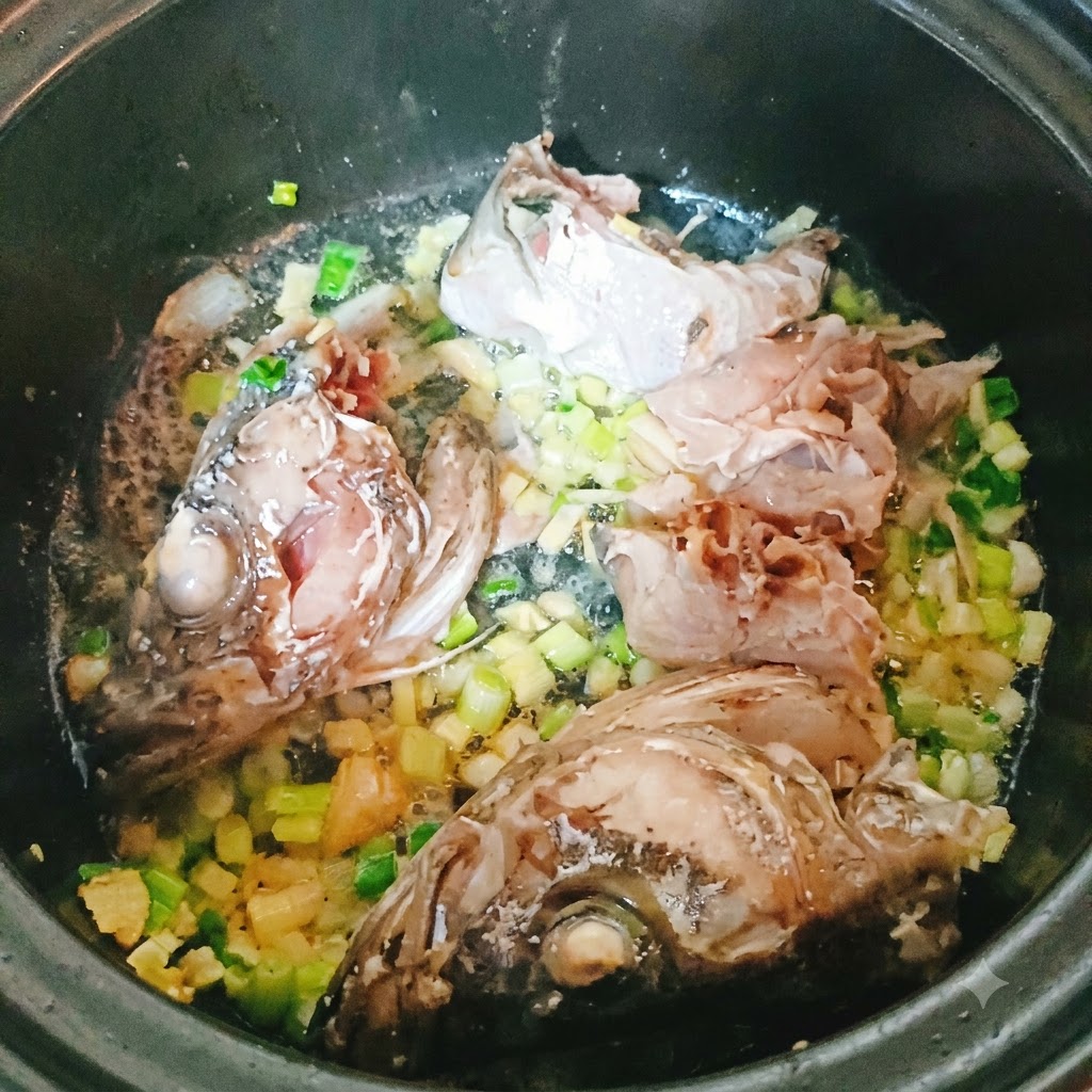 Pollock fish pieces and head frying in a pot with chopped aromatics.