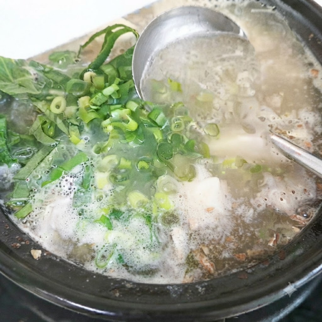 Fresh perilla leaves and chopped green onions being added to the finished soup pot.