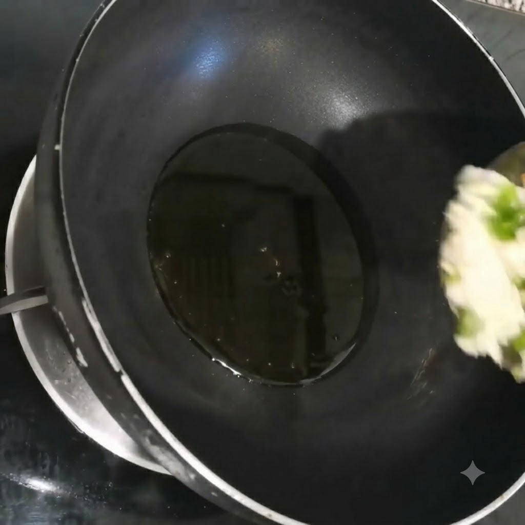 Finely chopped scallions, garlic, and cilantro sizzling in hot oil inside a black wok.