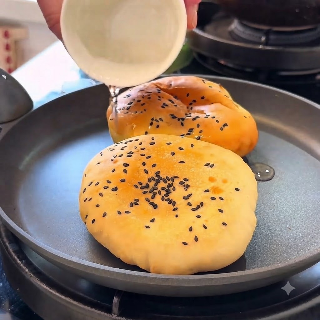 Burger buns being heated in a pan with water while covered.