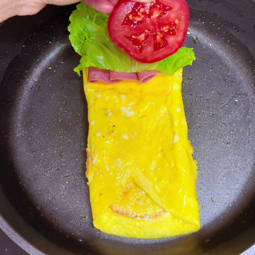 A slice of red tomato being added on top of the lettuce leaf layer.