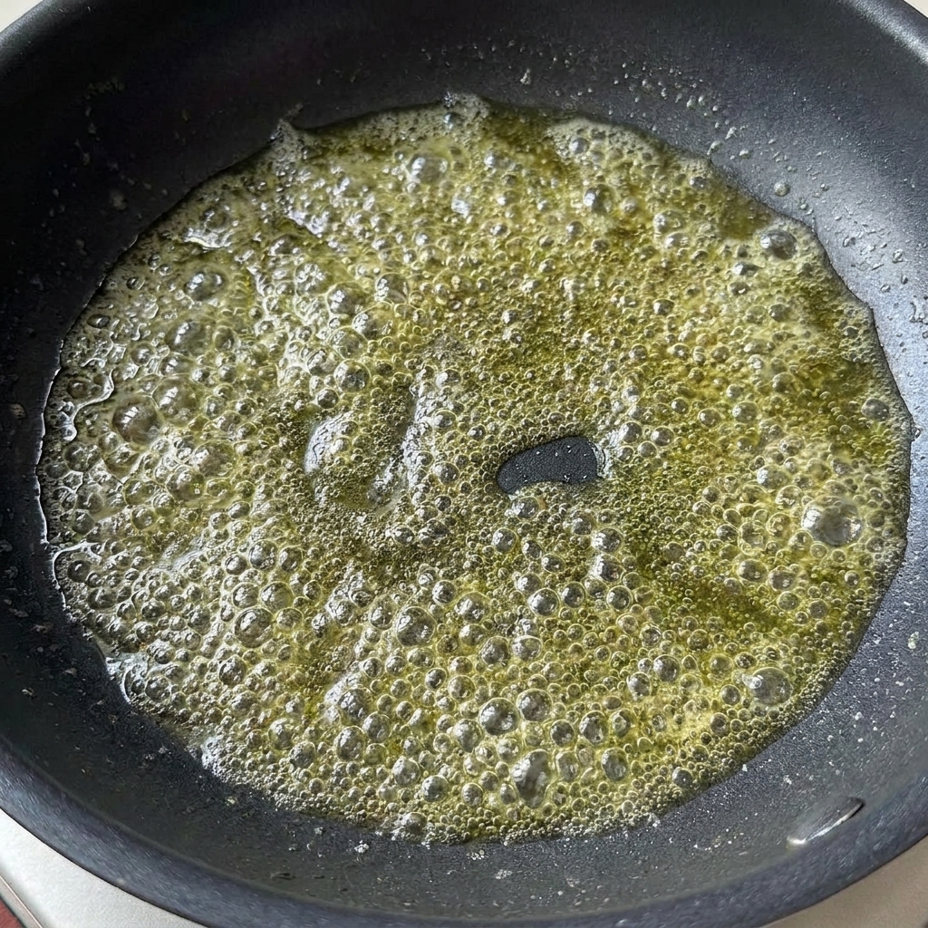 Light soy sauce and tomato paste added to bubbling melted butter in a pan.