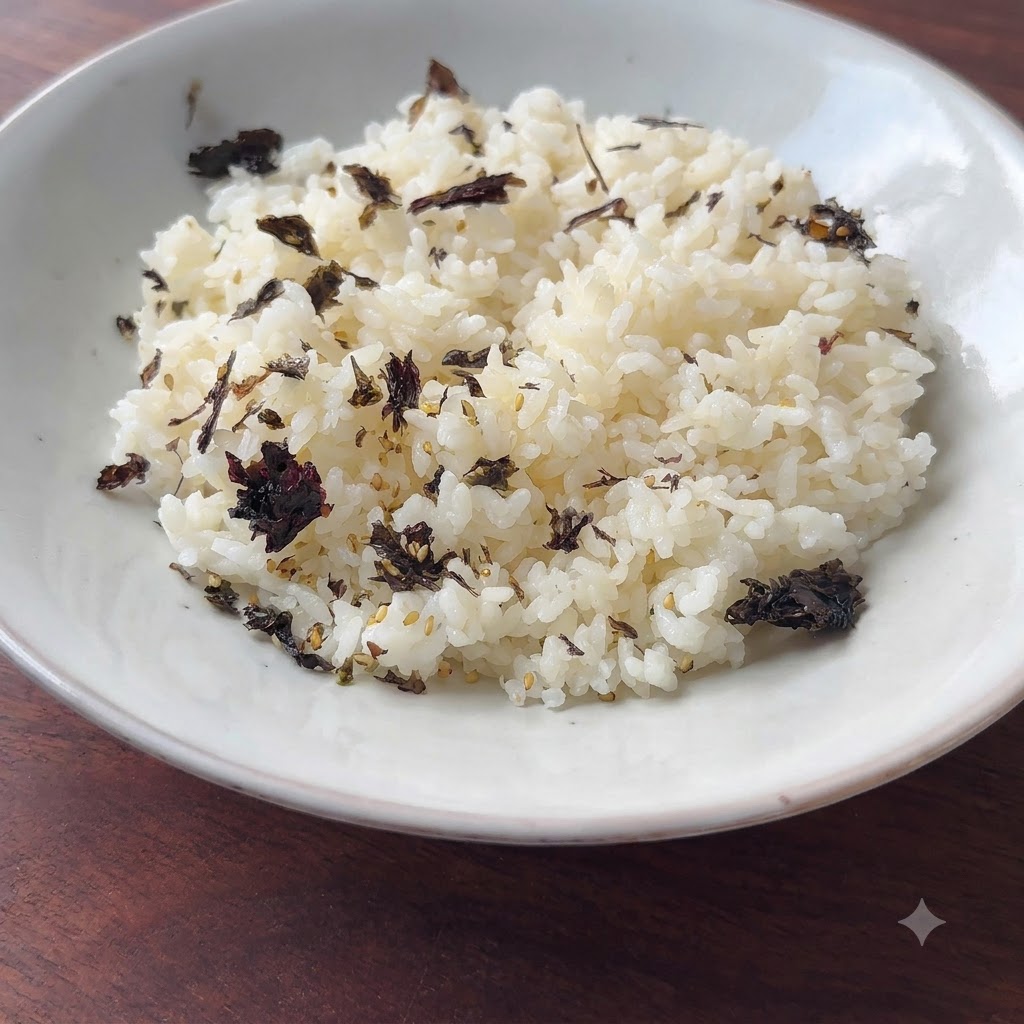 Seasoned rice garnished with dark flakes in a white bowl, ready for assembly.