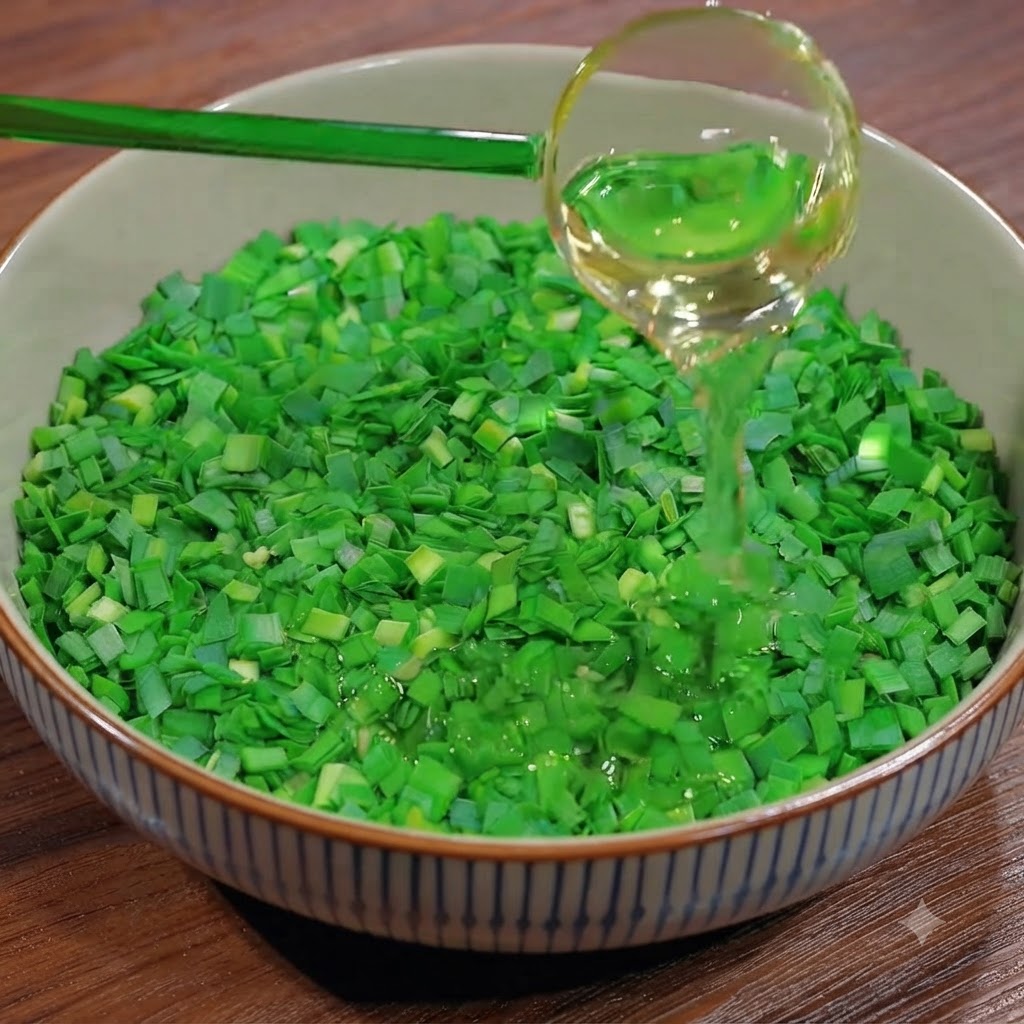 A ladle pouring cooking oil over a bowl filled with freshly chopped green chives.