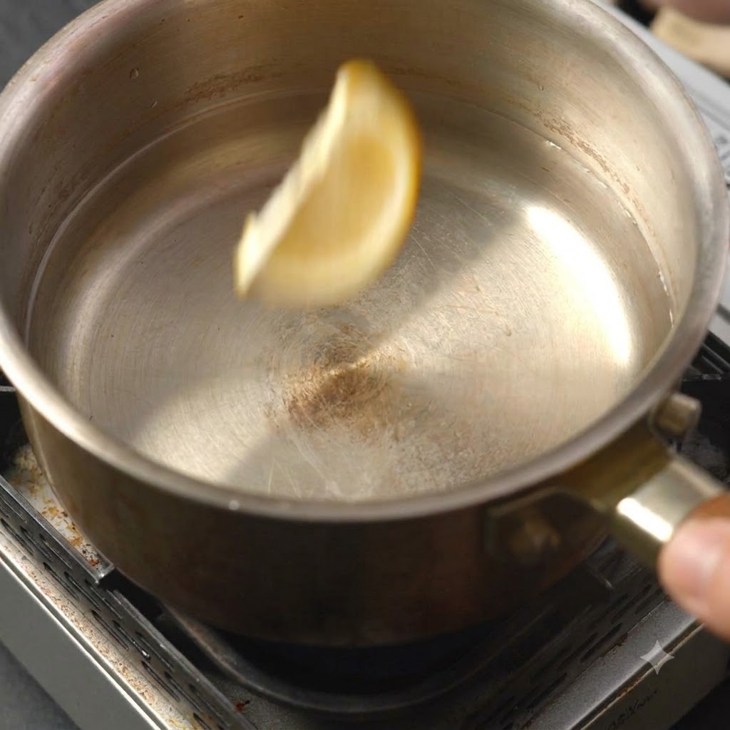 A single lemon slice falling into the pot of liquid.