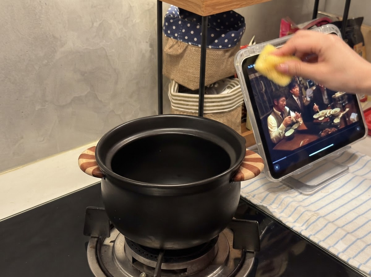A small black ceramic pot sitting on a gas stove burner.