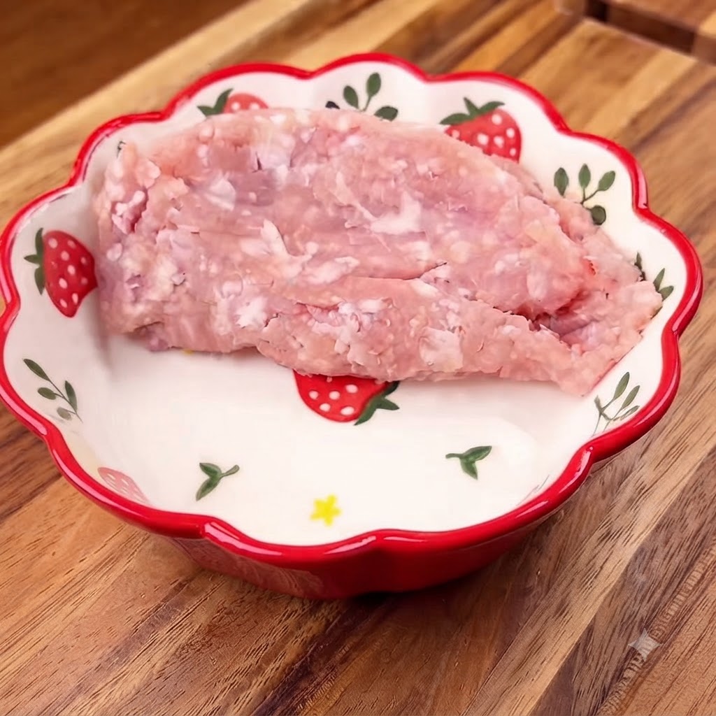 Minced pork placed inside a floral bowl with chopped green onions on top.