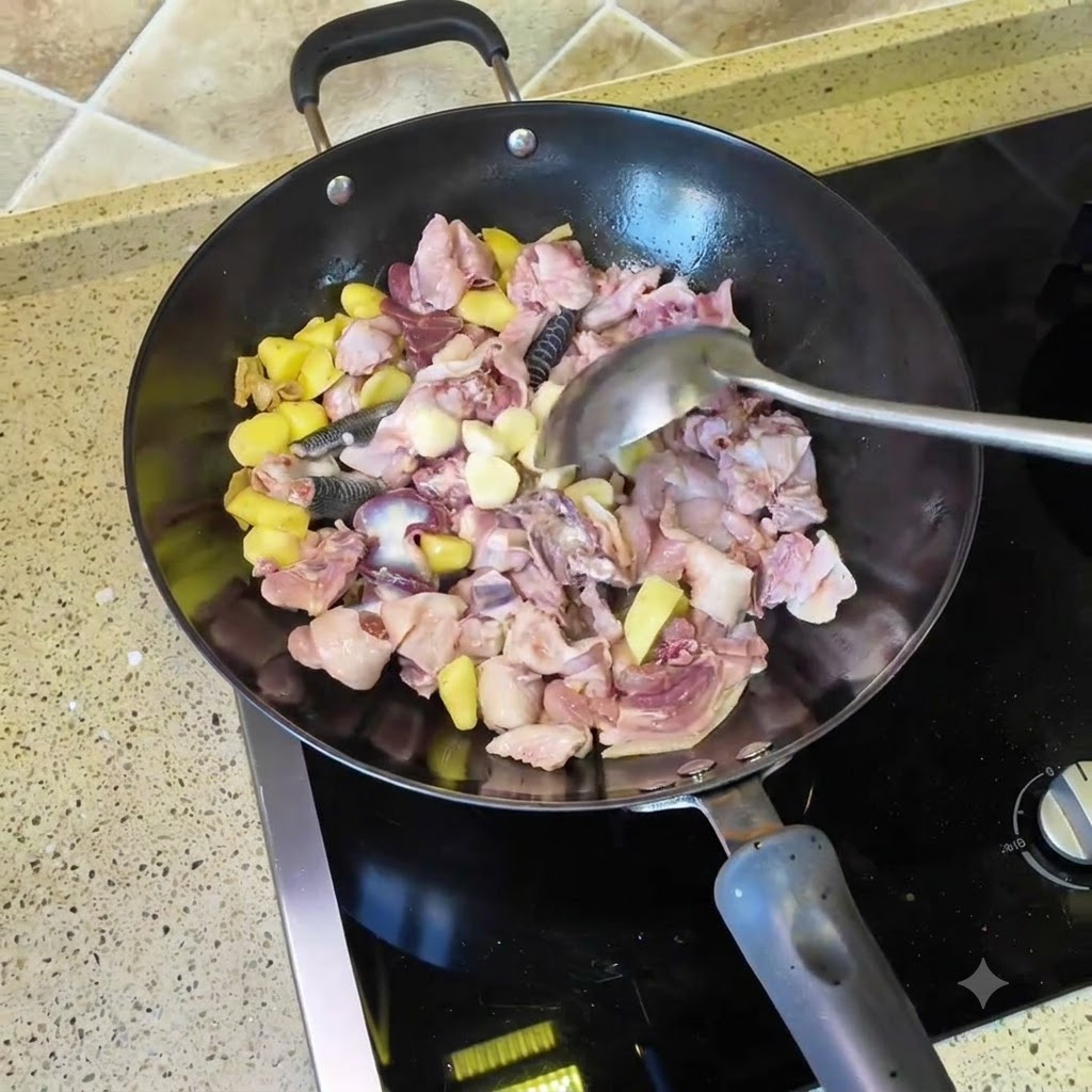 Garlic cloves and dried chili peppers being tossed into the wok with chicken and ginger pieces.
