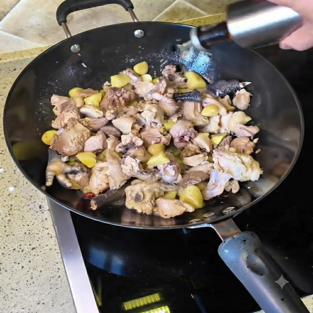 Yellow wine being poured from a bottle into the wok filled with stir-frying chicken chunks.
