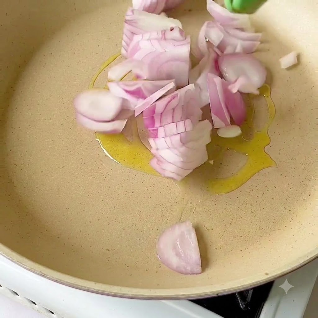 Sliced red onions sizzling in olive oil inside a pan.