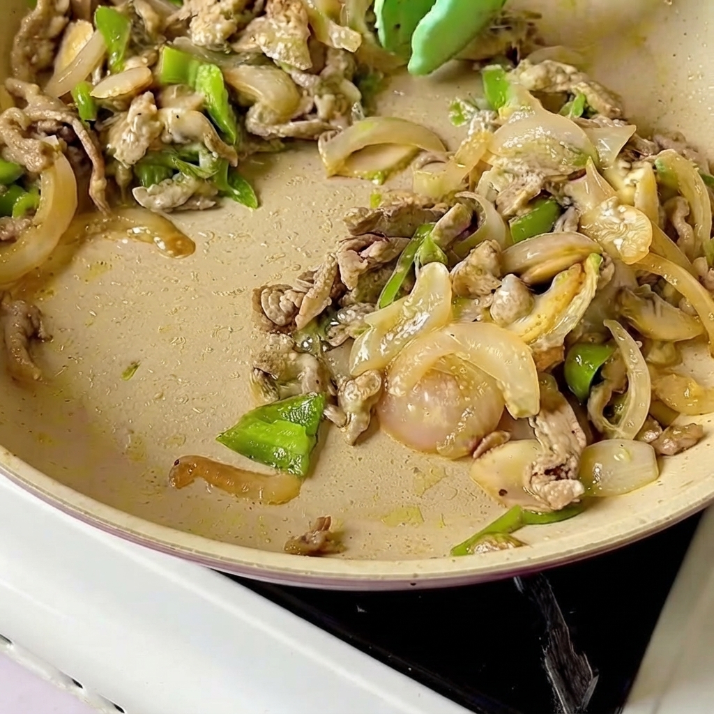 Cheese slices laid evenly on top of the warm beef and vegetable mixture in a pan.