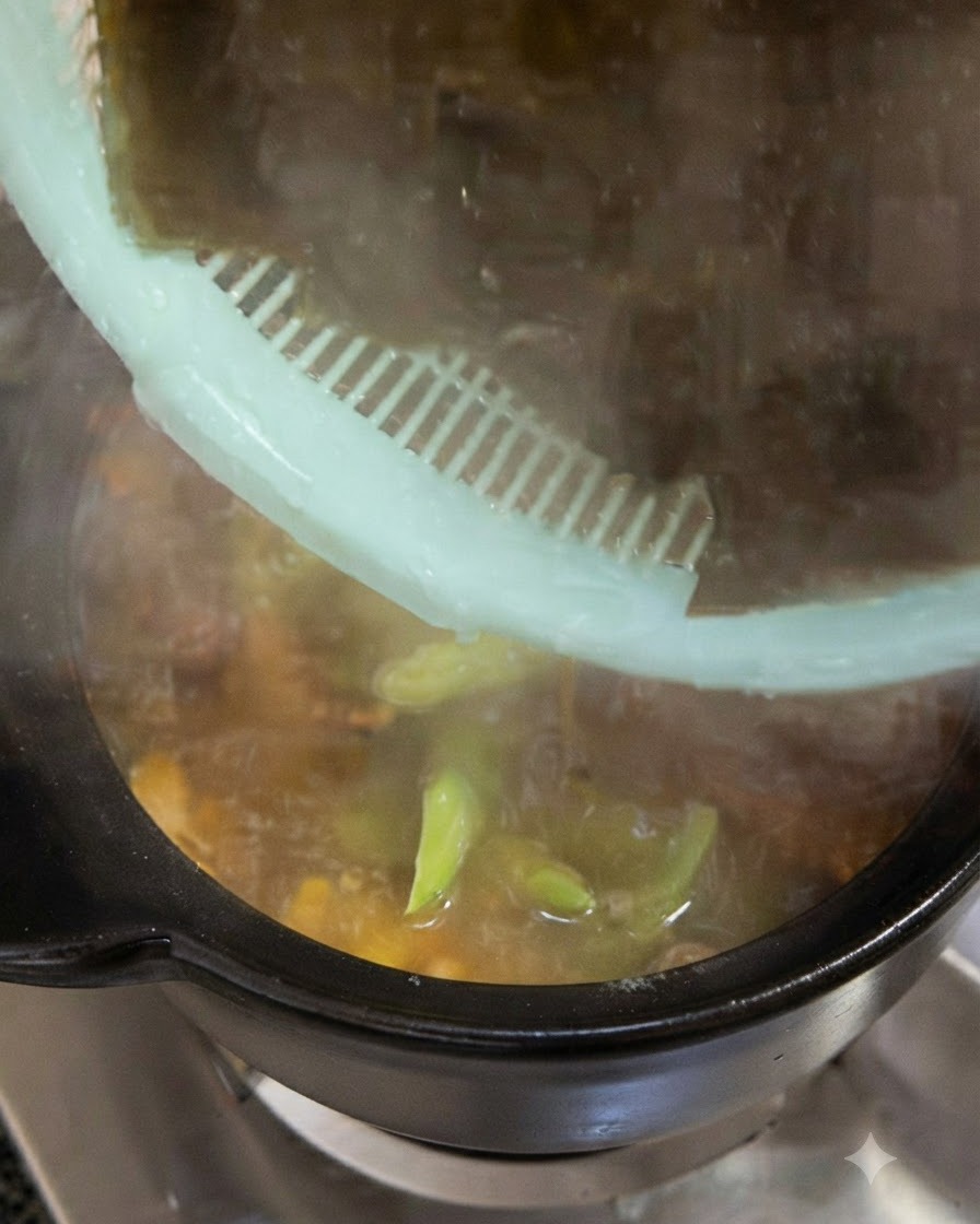 Large pieces of soaked dark green kelp being added into the cooking pot from a green strainer.