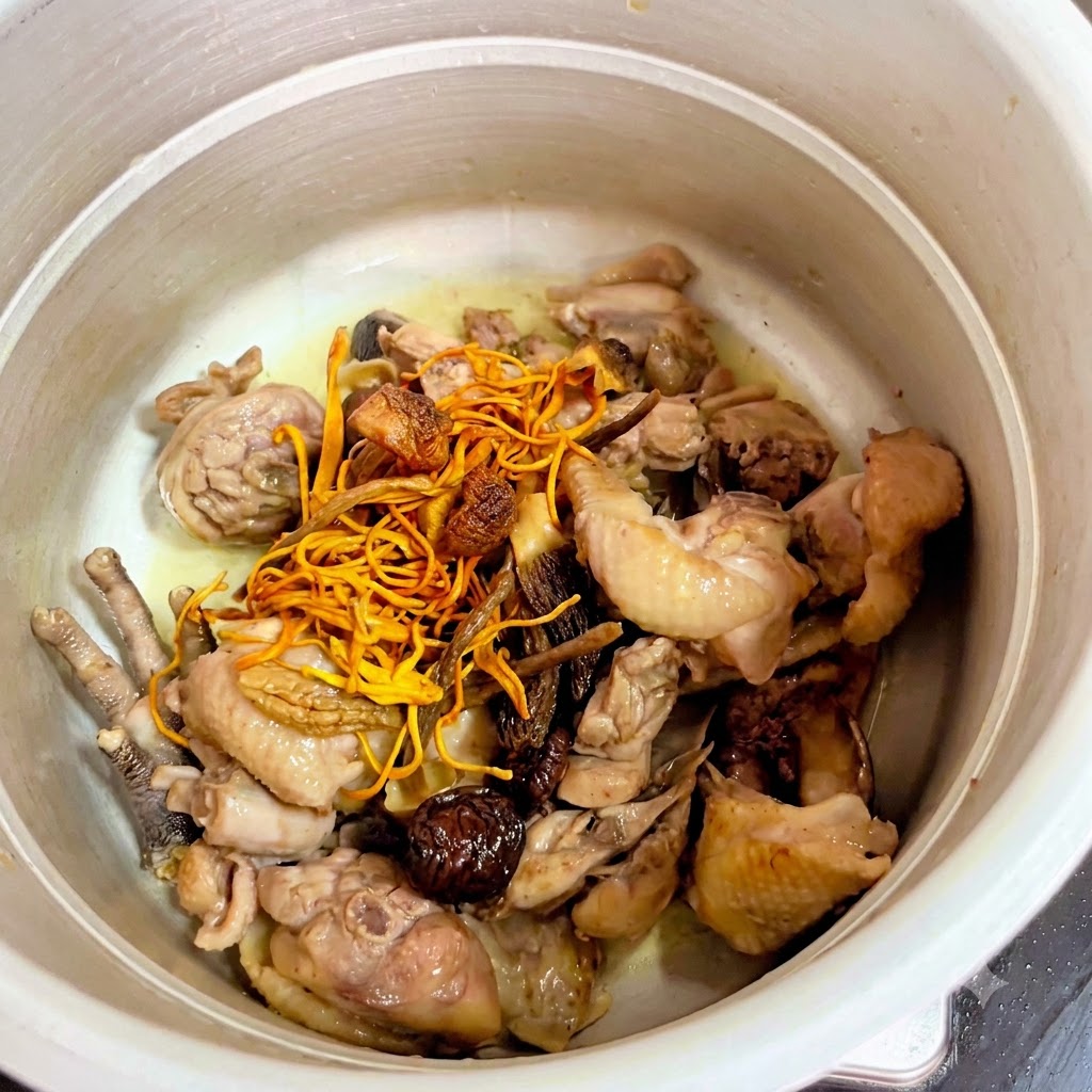 Dried mushrooms and yellow cordyceps flowers placed on top of the chicken inside the pressure cooker.