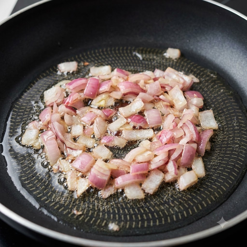 Diced red onions sizzling in hot cooking oil in a black non-stick skillet.