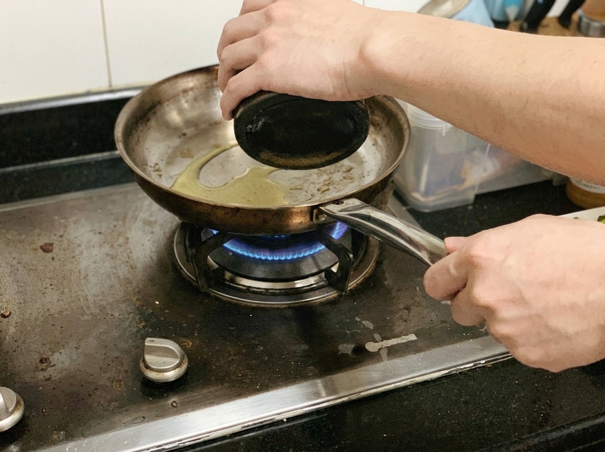 Slices of chicken breast being fried and seasoned with black pepper in a pan on the stove.