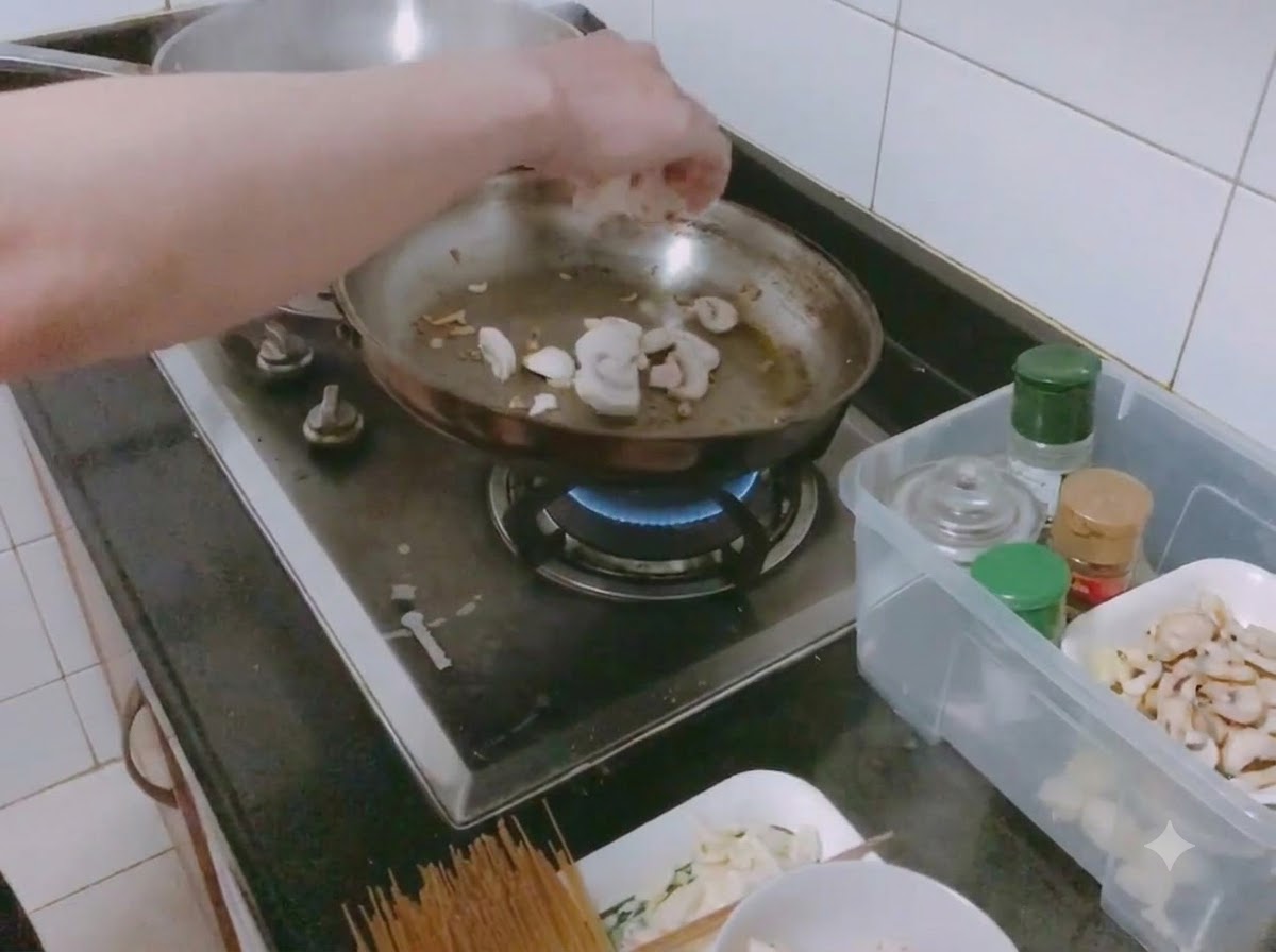Sliced white mushrooms and diced onions being sautéed with salt in a frying pan.