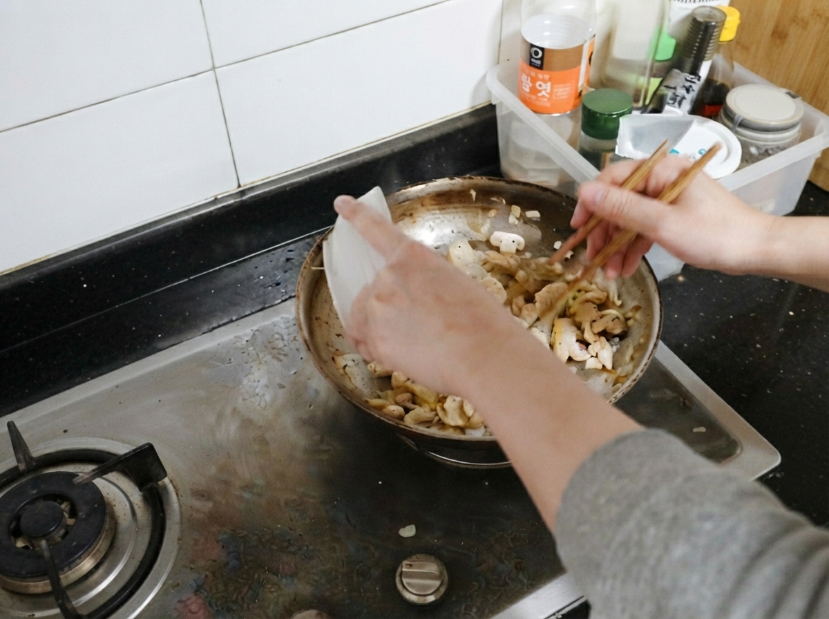 Cooked chicken slices being added back into the pan with mushrooms and onions.
