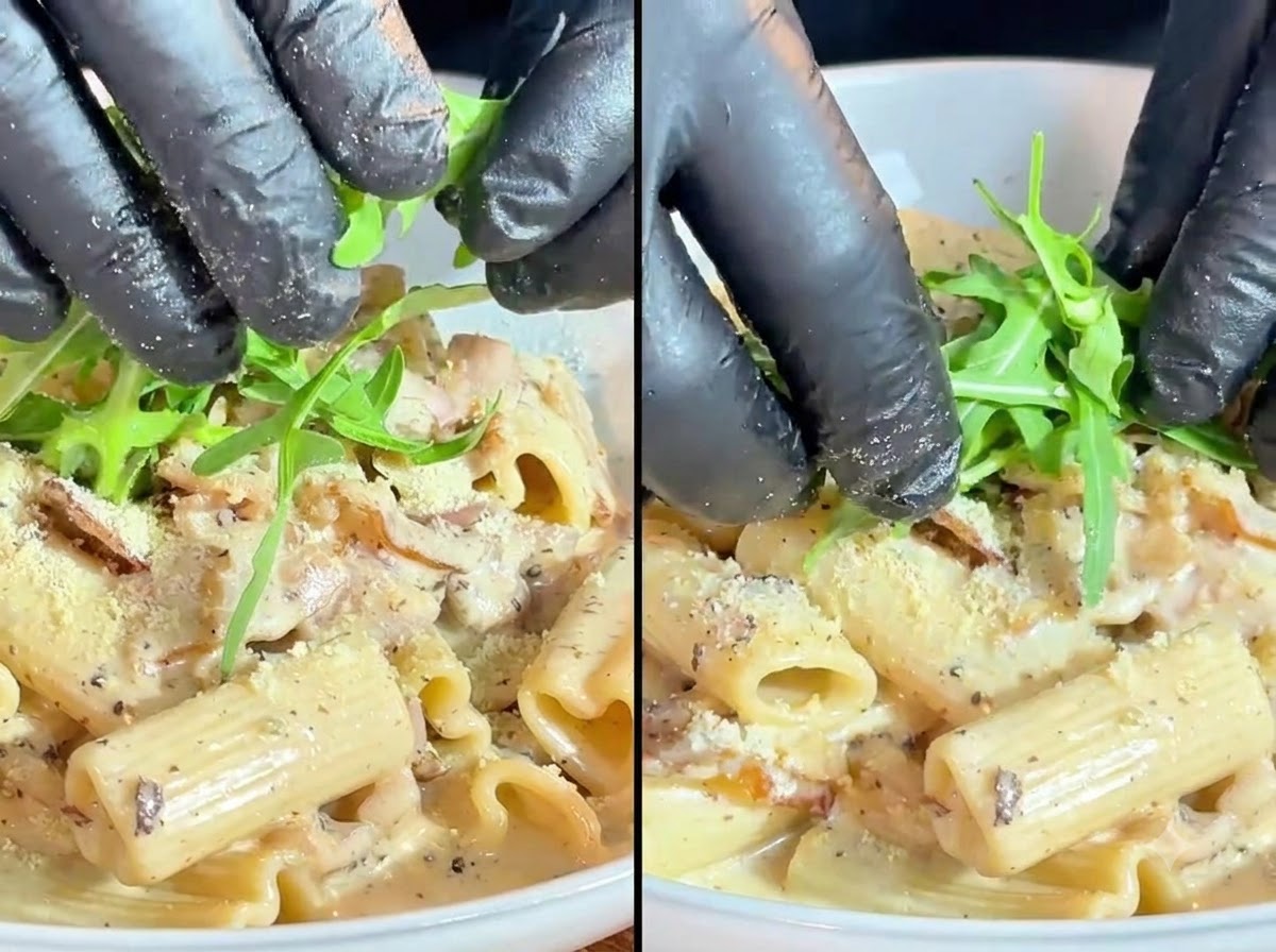 Fresh green arugula leaves and cherry tomatoes being carefully placed as a garnish over the creamy pasta.