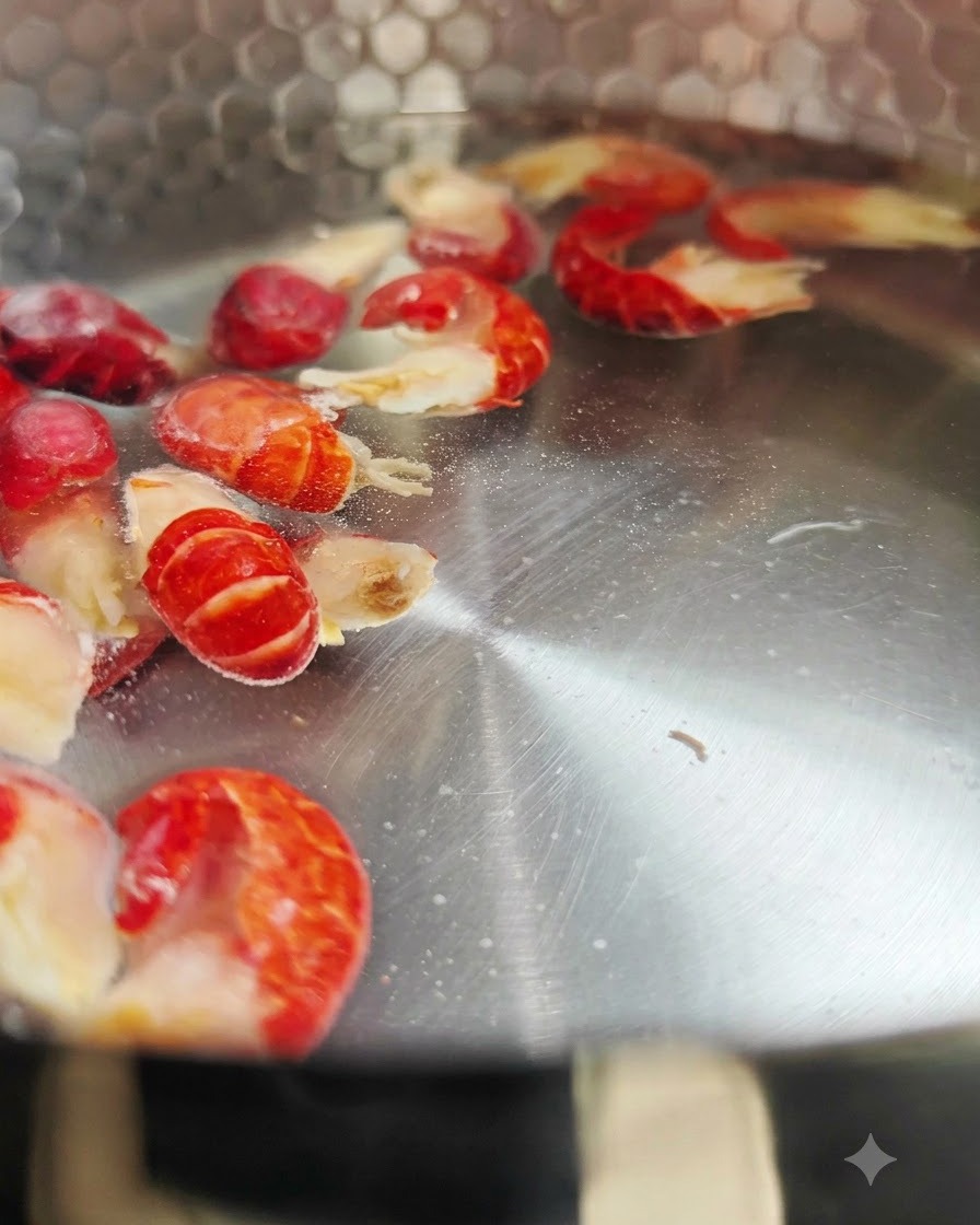 Frozen crawfish tails boiling inside a metal pot of hot water.