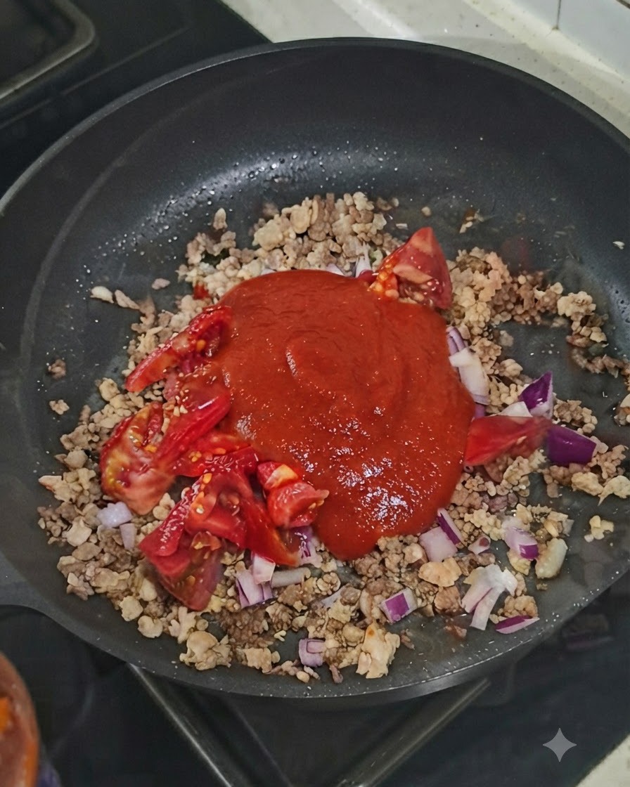A dollop of tomato paste sitting on top of the meat and vegetable mixture in the skillet.