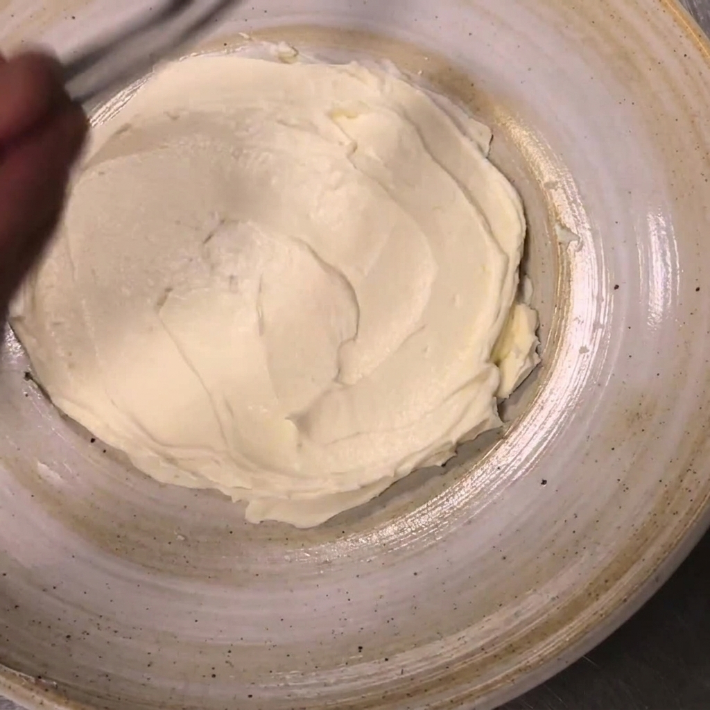 Cherry tomato halves being placed around the edges of spread ricotta cheese using tweezers.