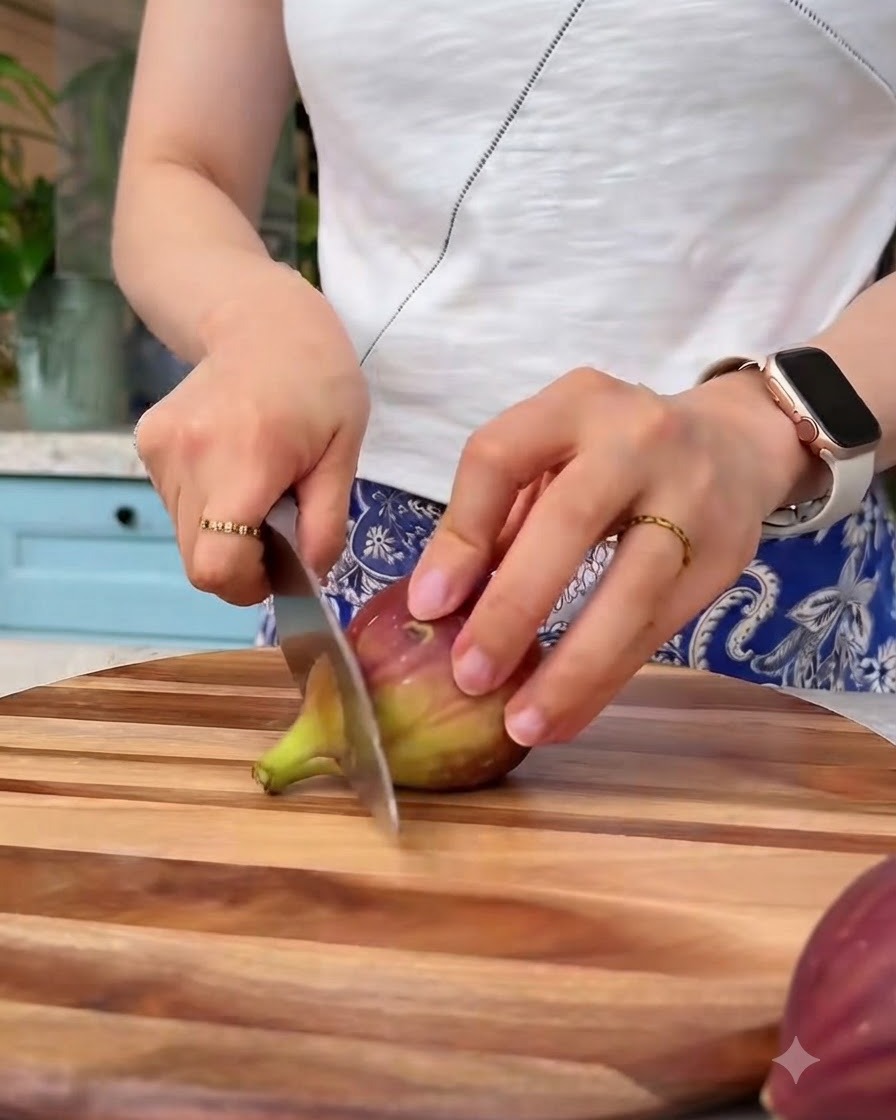 Fresh figs being sliced into small pieces with a knife on a wooden cutting board.