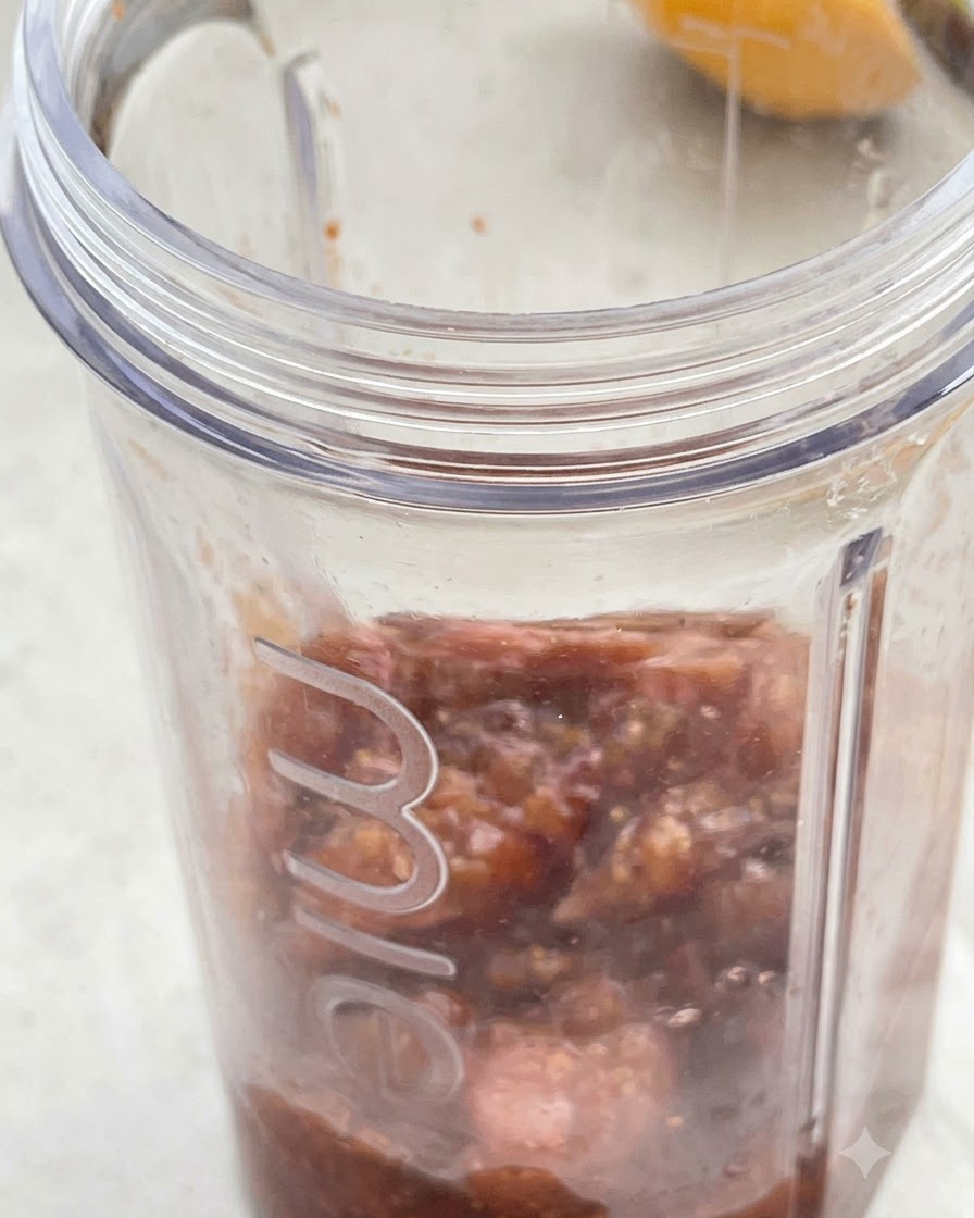 Cooked fig mixture and coconut cream poured inside a clear blender jar.