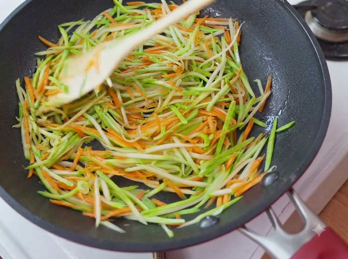 Shredded zucchini and carrots spread evenly in a circular layer inside the pan.