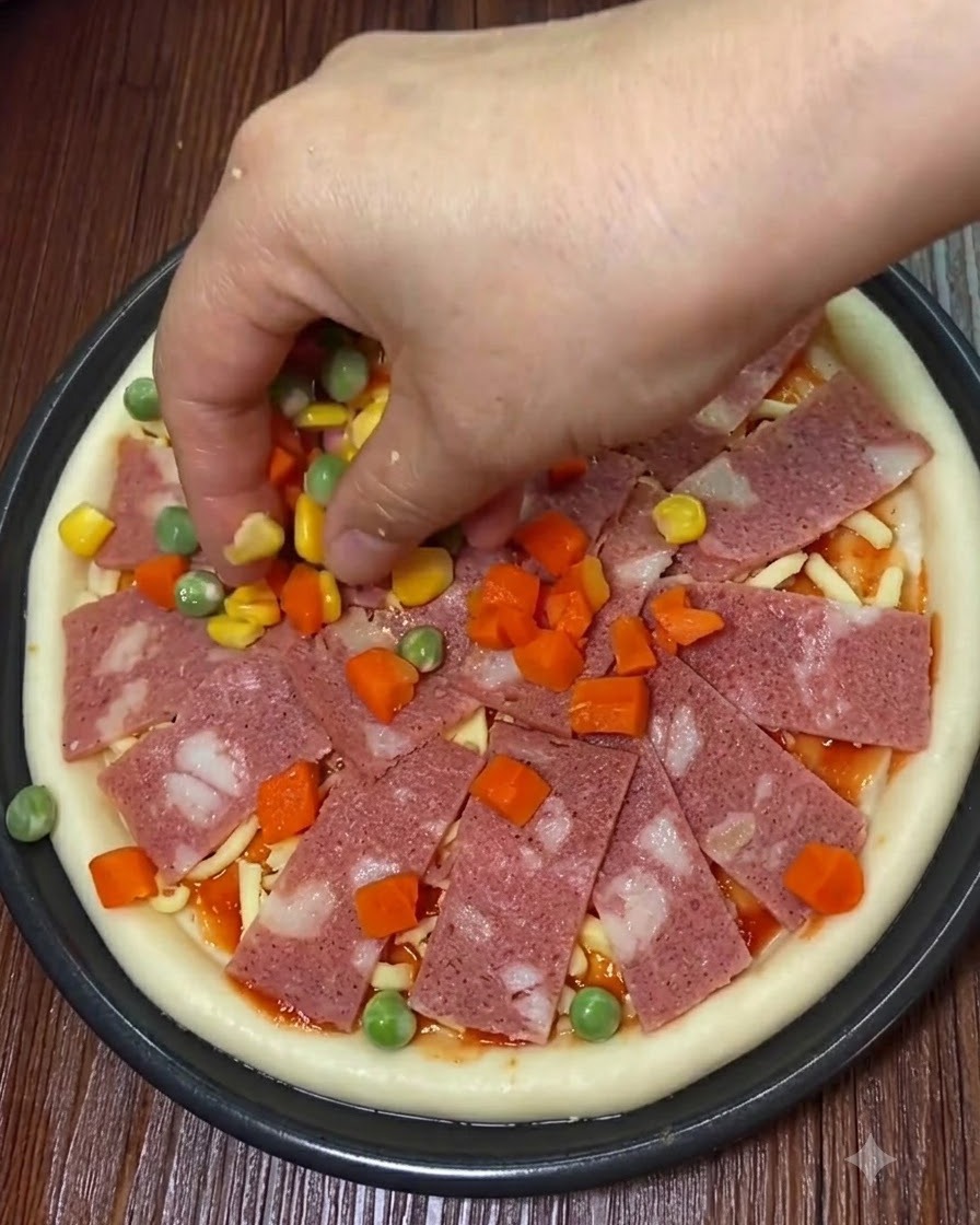 Bacon slices, sweet corn, and diced vegetables being placed onto the pizza.