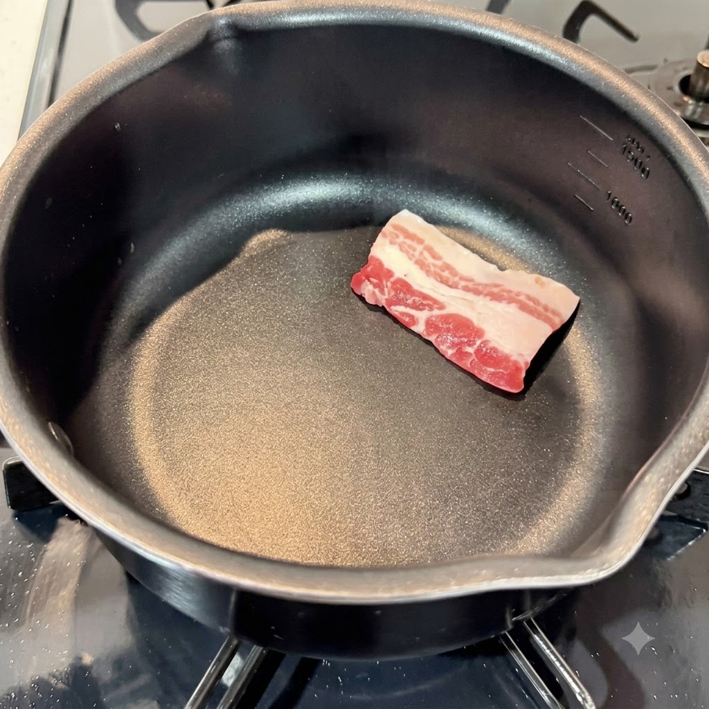 Raw pork belly slices laid out in an empty black cooking pot.