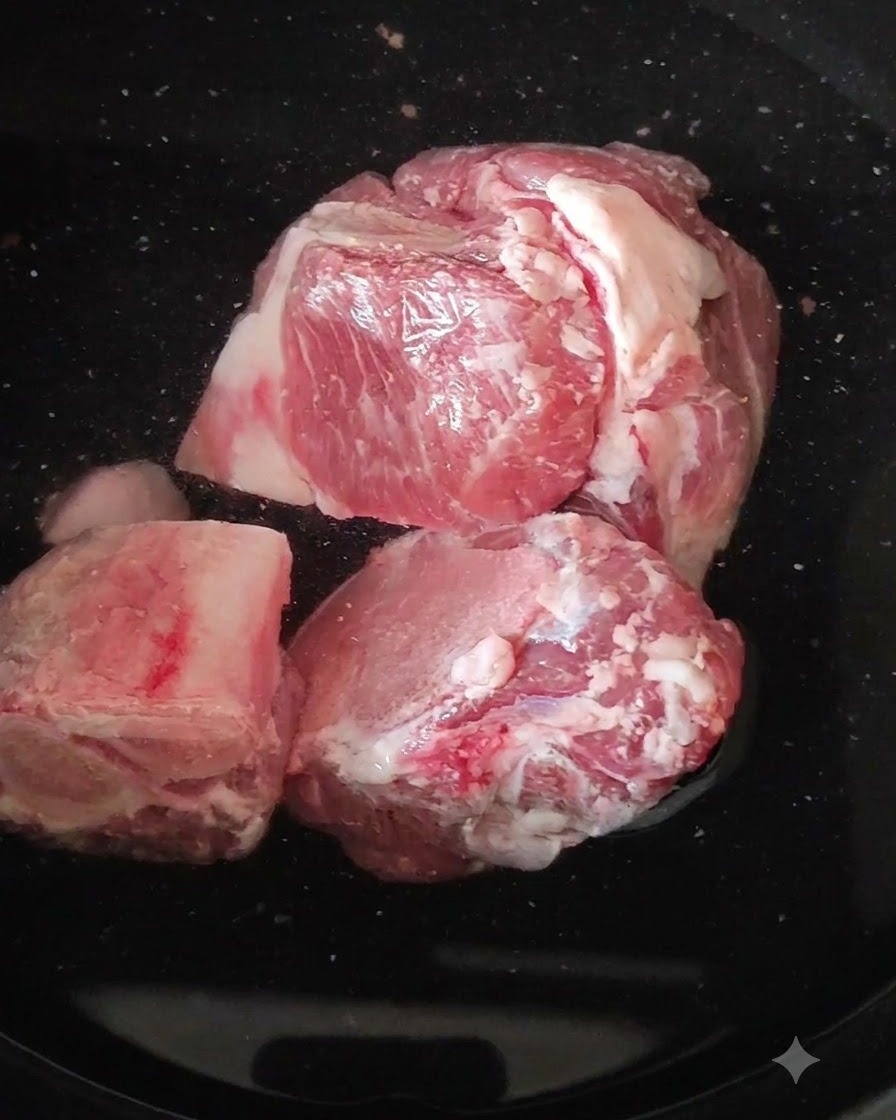 Raw pork leg bones sitting in a pot of boiling water.