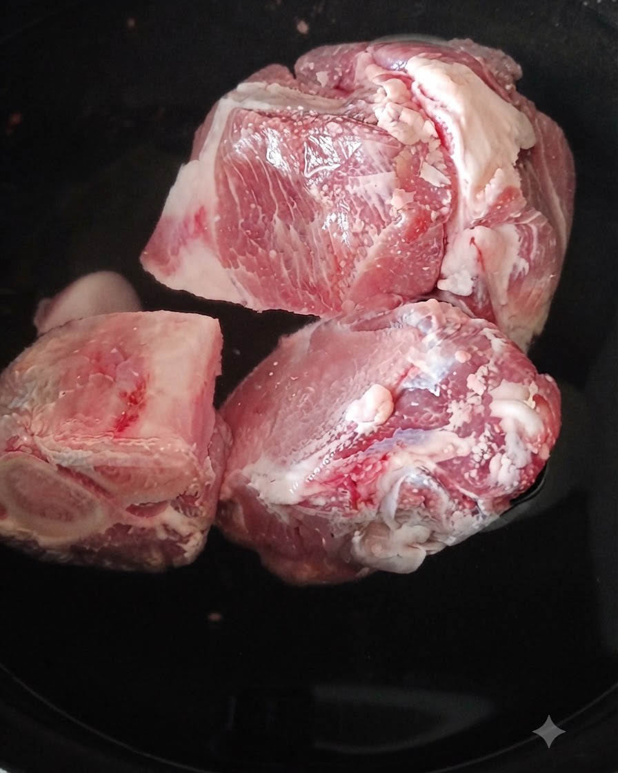Close-up of blanched pork leg bones being rinsed with hot water.