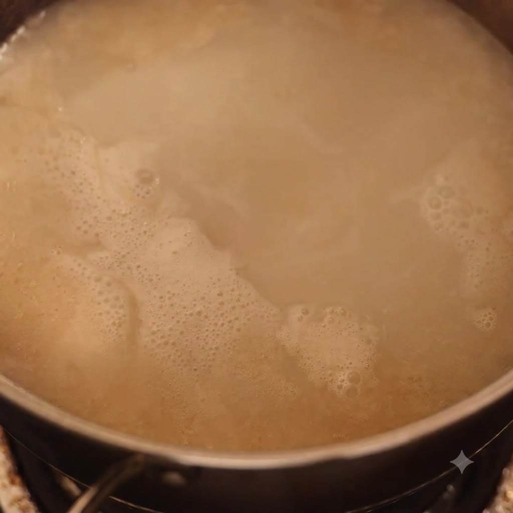 Mashed meat being mixed into a simmering pot of tonkotsu broth.
