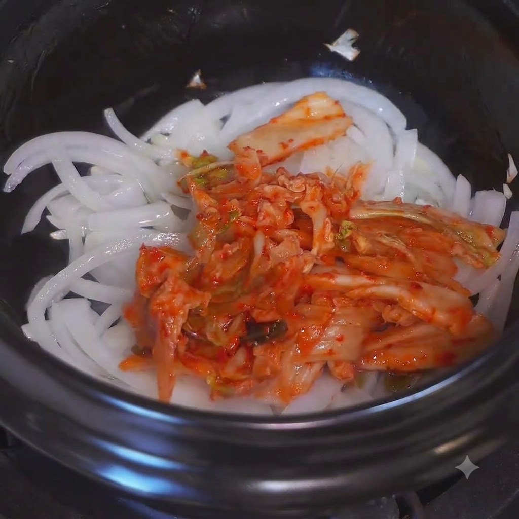 Chopped kimchi being mixed with sautéed onions in a pot.