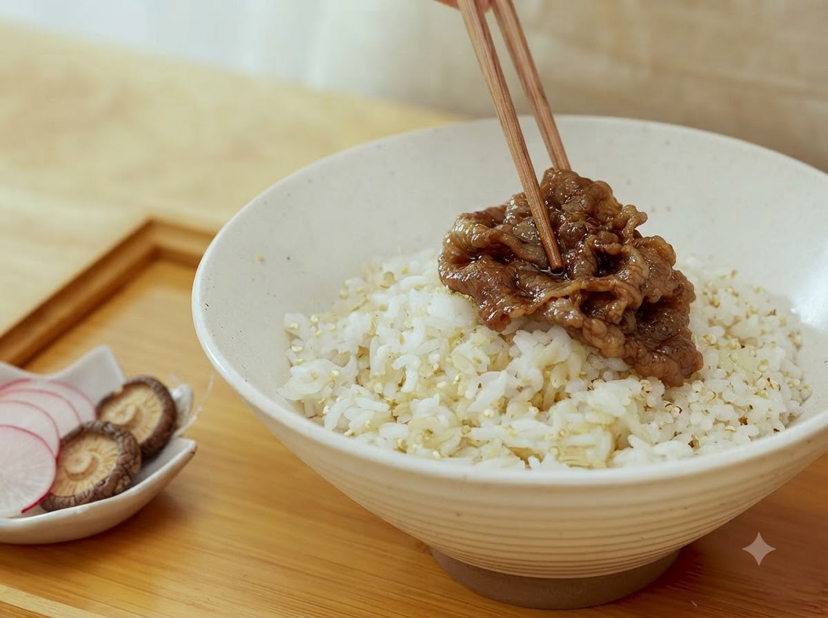 A pair of chopsticks placing cooked beef slices onto a bowl of cooked rice.