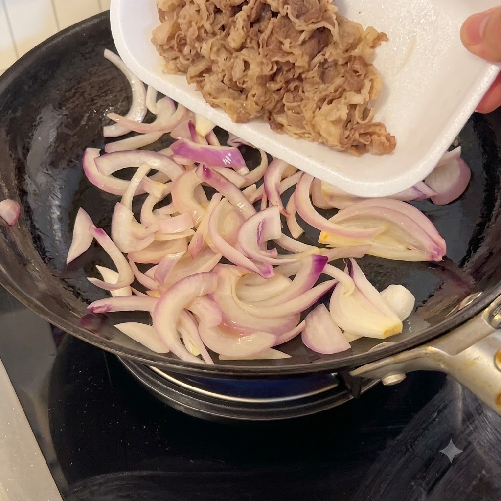 Thinly sliced beef being poured from a white foam tray into a skillet containing sautéed red onions.