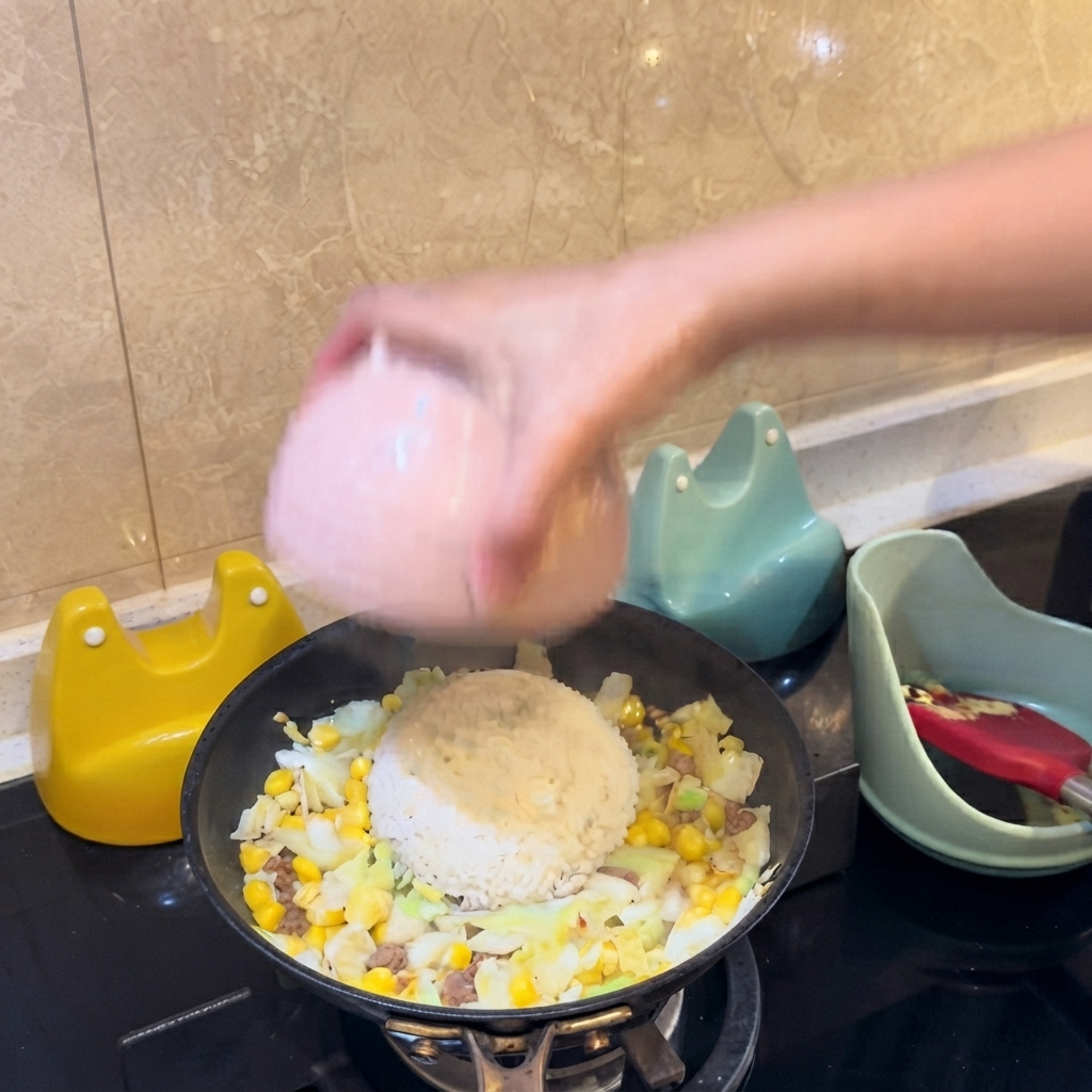 A pink bowl flipping a mound of white rice directly onto the center of the pans ingredients.