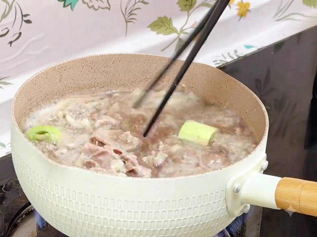Chopsticks retrieving blanched beef rolls from a boiling pot into a container.