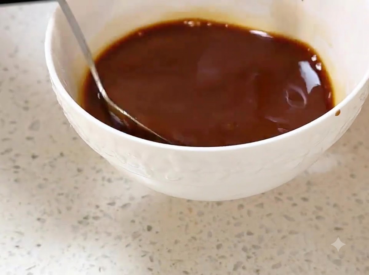 A cube of butter melting in a hot wok, spread around with a spatula.
