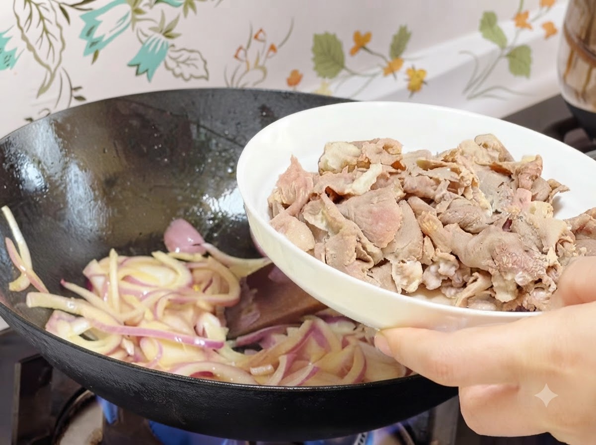 Blanched beef rolls being poured from a white plate into the wok with cooked onions.